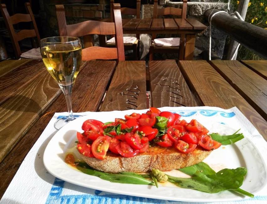 Bruschetta con pomodori freschi e basilico, accompagnata da un bicchiere di vino bianco.