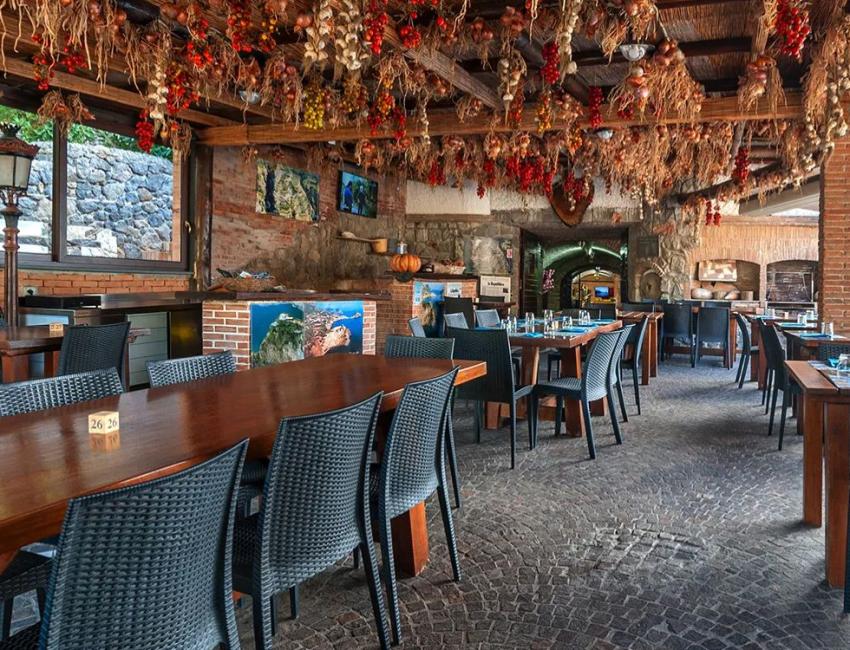 Ristorante rustico con decorazioni appese e tavoli in legno, atmosfera accogliente.